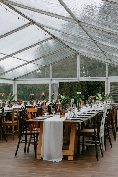 A marquee in a garden, with vintage furniture and elegant floral arrangements