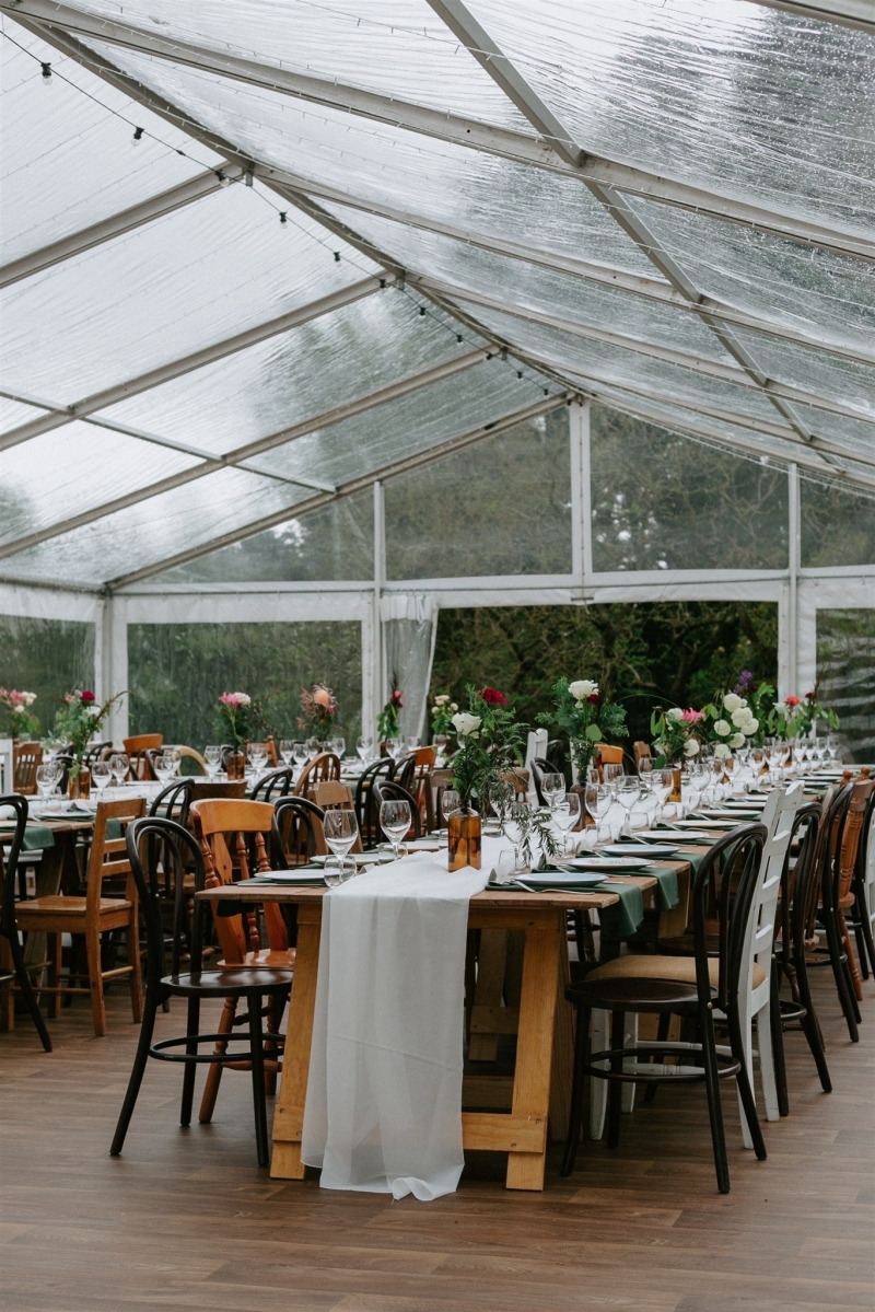 A marquee in a garden, with vintage furniture and elegant floral arrangements