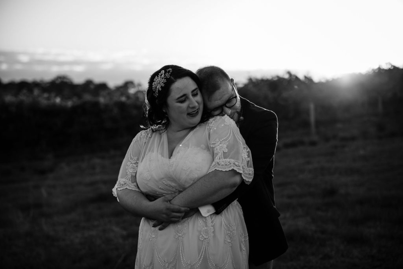 A bride and groom share a comforting embrace during a wedding portrait session