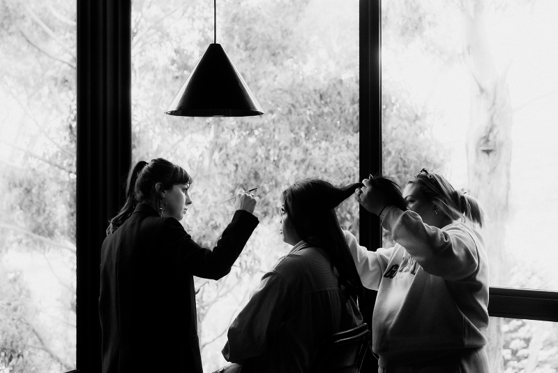 A bride has a hair and makeup artist getting her ready for her wedding day in their Hobart Airbnb