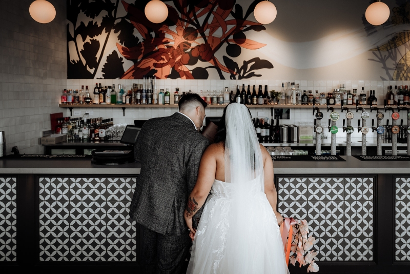 A bride and groom are dressed glamorously in wedding clothes as they order drinks from a bar in Hobart, Tasmania